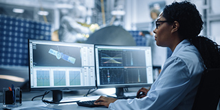 Engineer analyzing aircraft maintenance data on dual monitors, showing how MRO management software supports compliance, performance tracking, and digital transformation.